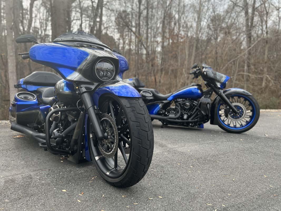 Pair of blue motorbikes parked on side of road.