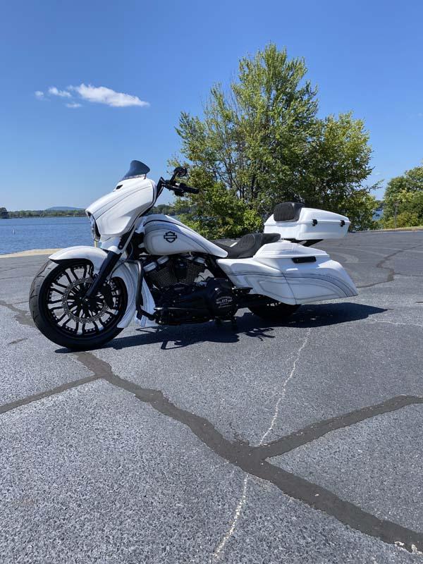 White motorcycle parked on side of road, under clear blue sky.